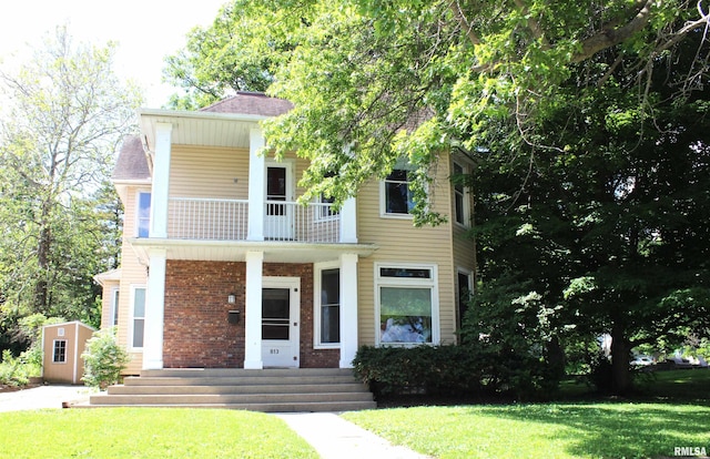 view of front of house featuring a front lawn and a balcony