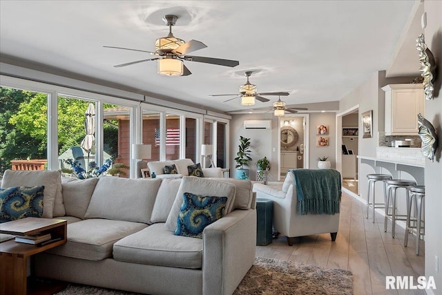 living room featuring ceiling fan, light wood-type flooring, and a wall unit AC