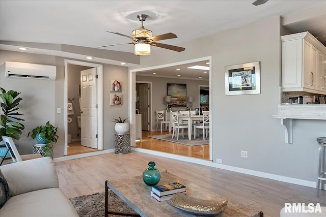 living room featuring light hardwood / wood-style flooring, a wall mounted AC, and ceiling fan