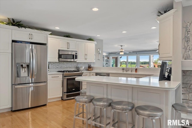 kitchen featuring a breakfast bar area, kitchen peninsula, white cabinetry, and stainless steel appliances