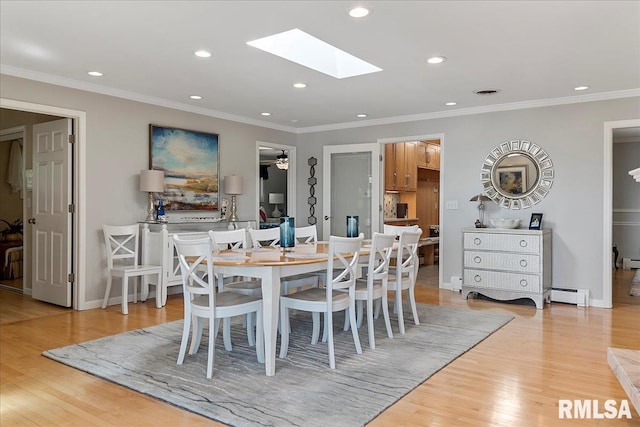 dining space with ornamental molding, light wood-type flooring, baseboard heating, and a skylight