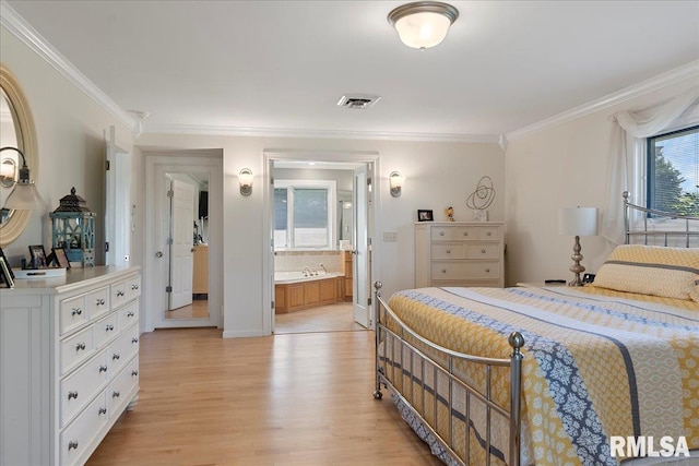 bedroom featuring light wood-type flooring, crown molding, and connected bathroom