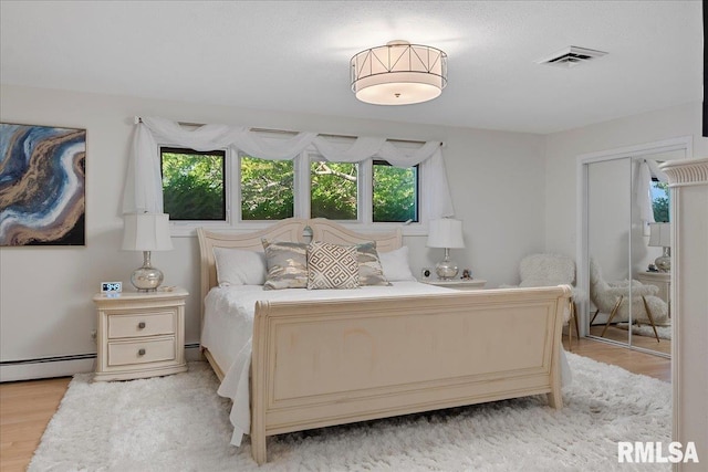 bedroom featuring light hardwood / wood-style flooring and a baseboard heating unit