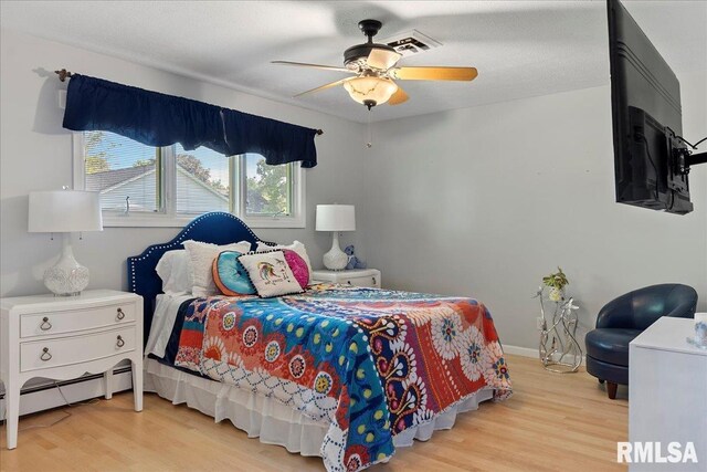 bedroom featuring baseboard heating, ceiling fan, and light hardwood / wood-style floors