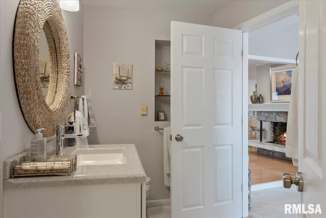 bathroom featuring vanity, toilet, and a fireplace