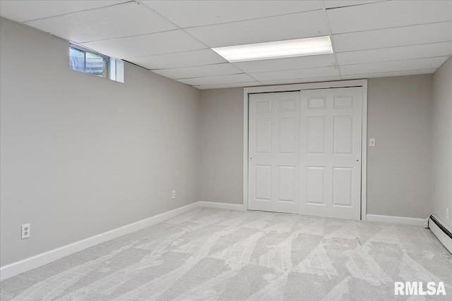 unfurnished bedroom featuring a paneled ceiling, light colored carpet, a baseboard radiator, and a closet