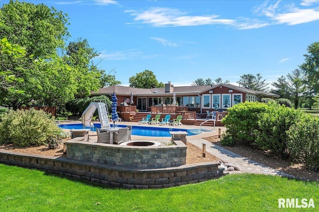 view of swimming pool featuring a patio, a wooden deck, and a water slide