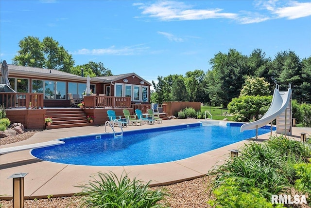 view of swimming pool featuring a patio area, a water slide, and a wooden deck