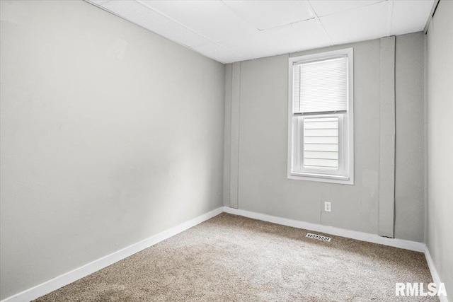 carpeted empty room featuring a paneled ceiling