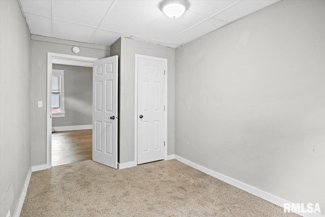 unfurnished bedroom featuring light colored carpet and a drop ceiling