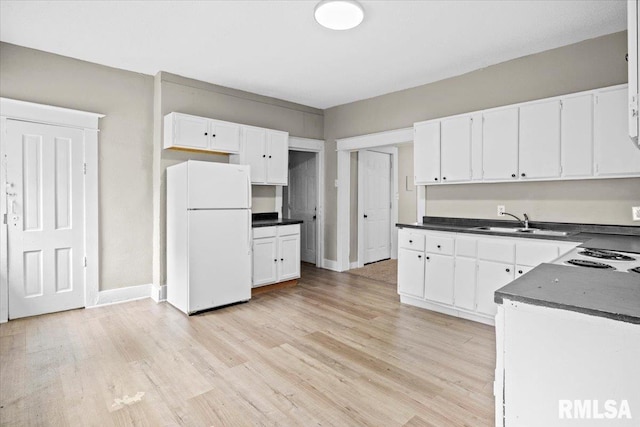 kitchen with white fridge, white cabinetry, sink, and light hardwood / wood-style flooring