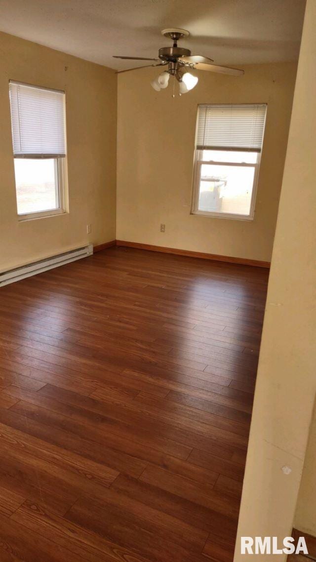 spare room with ceiling fan, dark wood-type flooring, and a baseboard heating unit