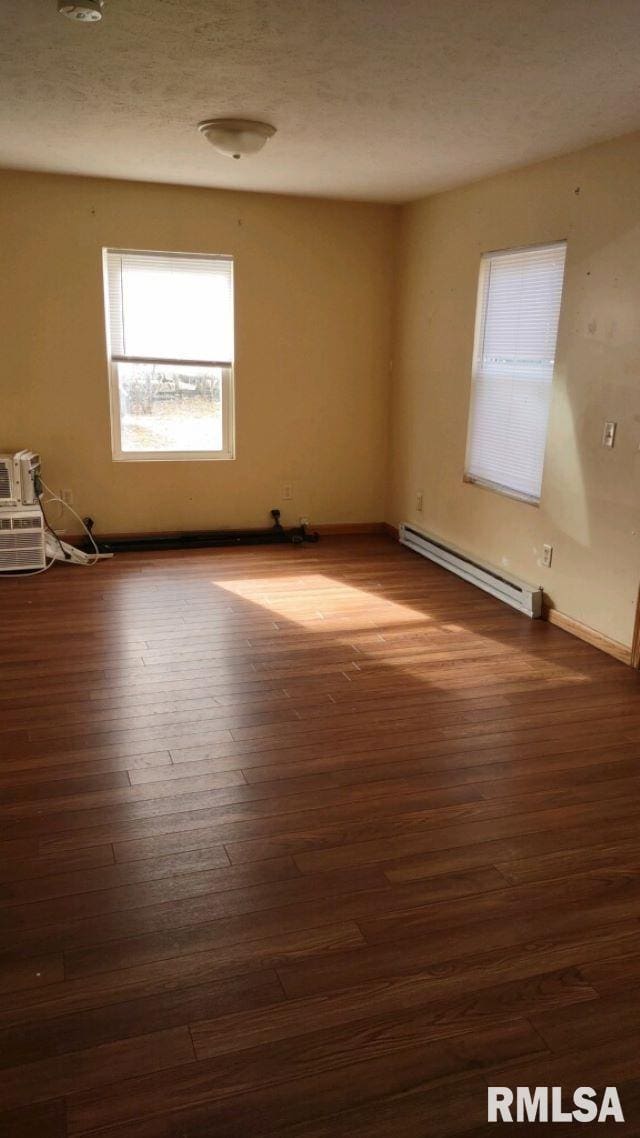 empty room with dark hardwood / wood-style flooring and baseboard heating