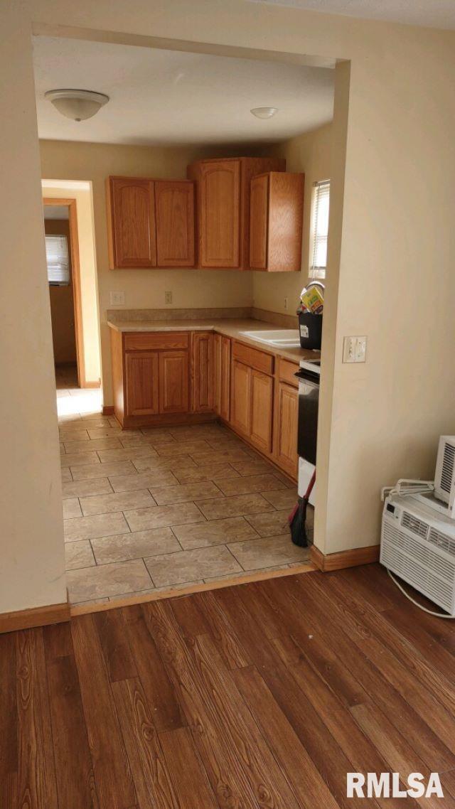 kitchen with stove, a wall mounted AC, and sink