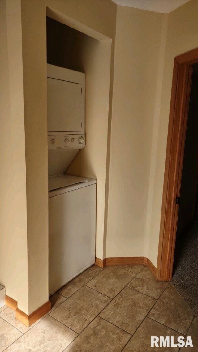 laundry area featuring light tile patterned floors and stacked washer / dryer