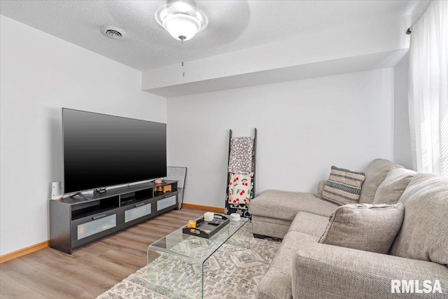 living room featuring a textured ceiling, hardwood / wood-style flooring, and ceiling fan