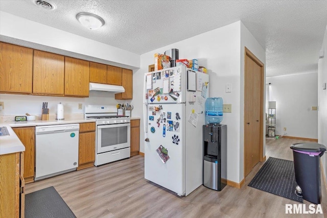 kitchen with light hardwood / wood-style floors, white appliances, and a textured ceiling