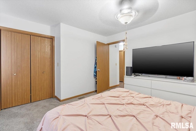 bedroom with a textured ceiling, ceiling fan, light carpet, and a closet