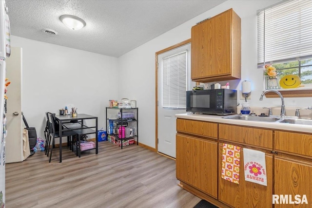 kitchen with a textured ceiling, light hardwood / wood-style floors, and sink