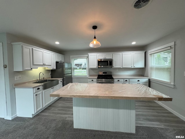 kitchen featuring stainless steel appliances, hanging light fixtures, light countertops, and white cabinets