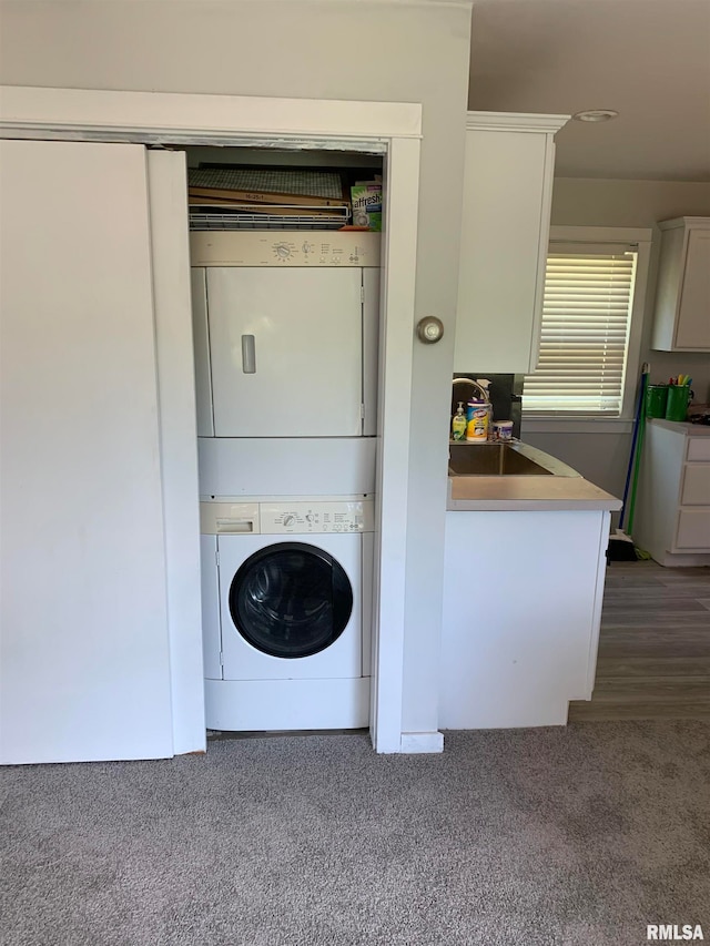 laundry room featuring stacked washing maching and dryer, sink, and dark colored carpet