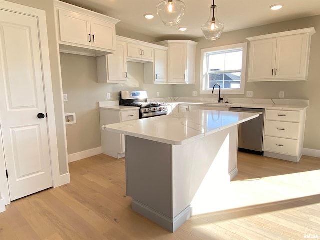 kitchen with stainless steel appliances, sink, pendant lighting, a center island, and white cabinetry