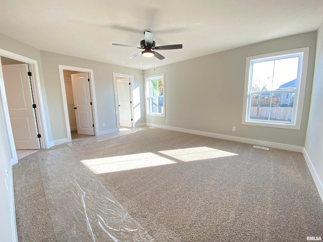 unfurnished bedroom featuring multiple windows, light colored carpet, and ceiling fan