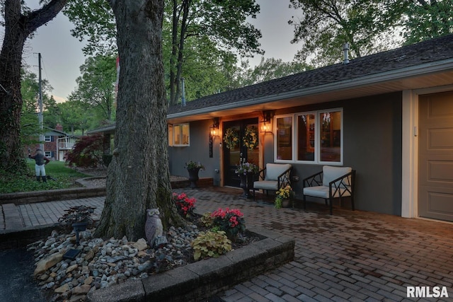 back house at dusk featuring a patio