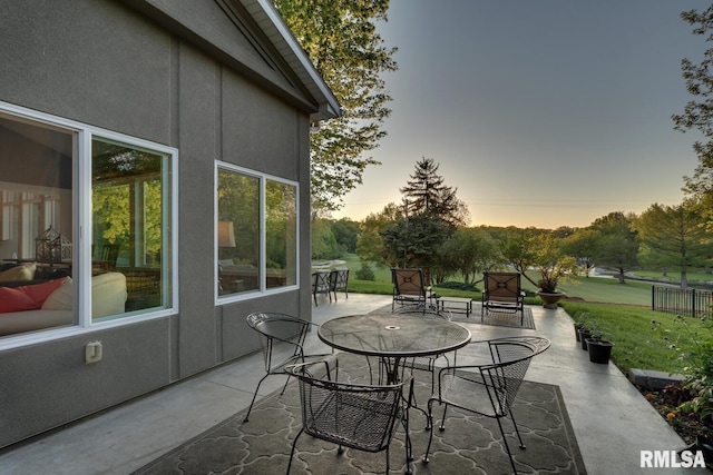 patio terrace at dusk featuring a lawn