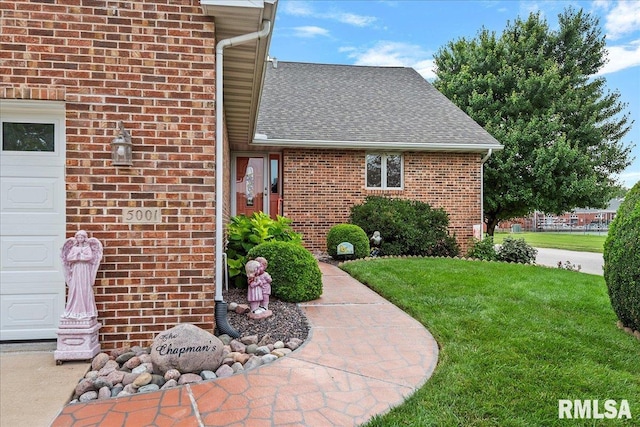 entrance to property featuring a lawn and a garage