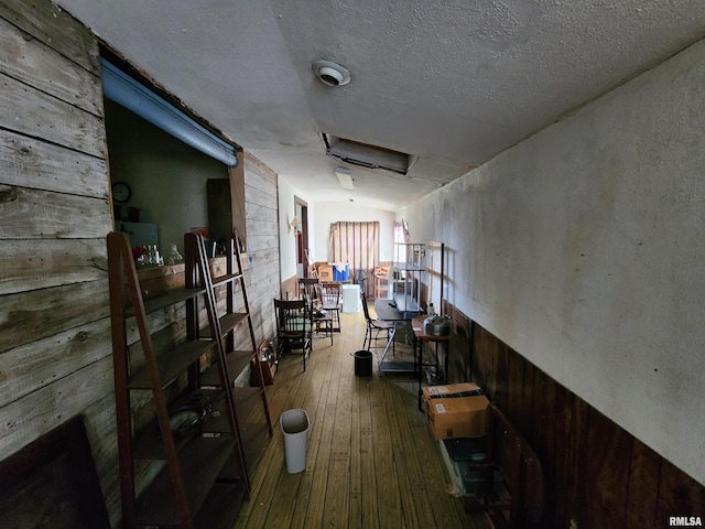 hallway featuring a textured ceiling, wood walls, and hardwood / wood-style floors