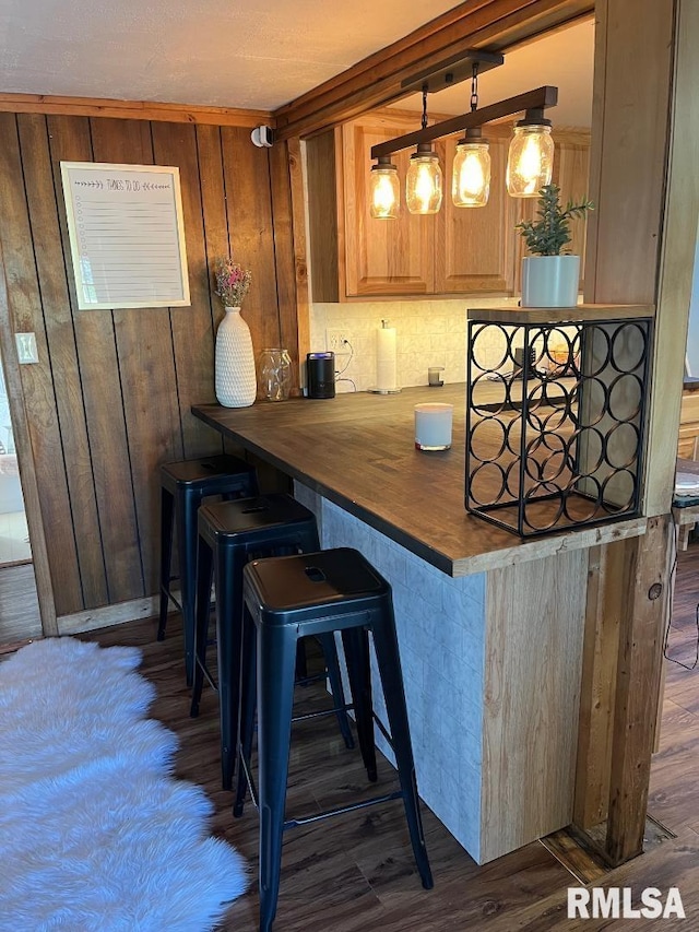 kitchen featuring decorative light fixtures, a kitchen bar, kitchen peninsula, and dark wood-type flooring