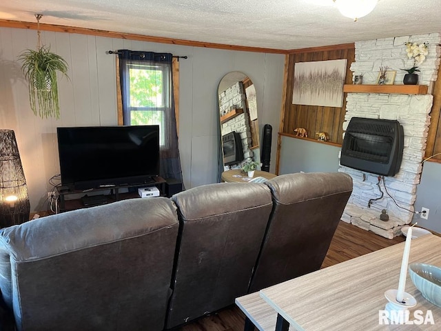 living room featuring ornamental molding, dark hardwood / wood-style flooring, a textured ceiling, and a stone fireplace