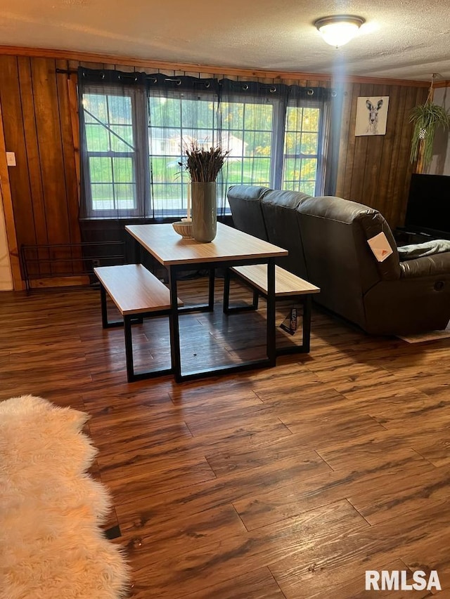 living room featuring plenty of natural light, wooden walls, a textured ceiling, and hardwood / wood-style flooring