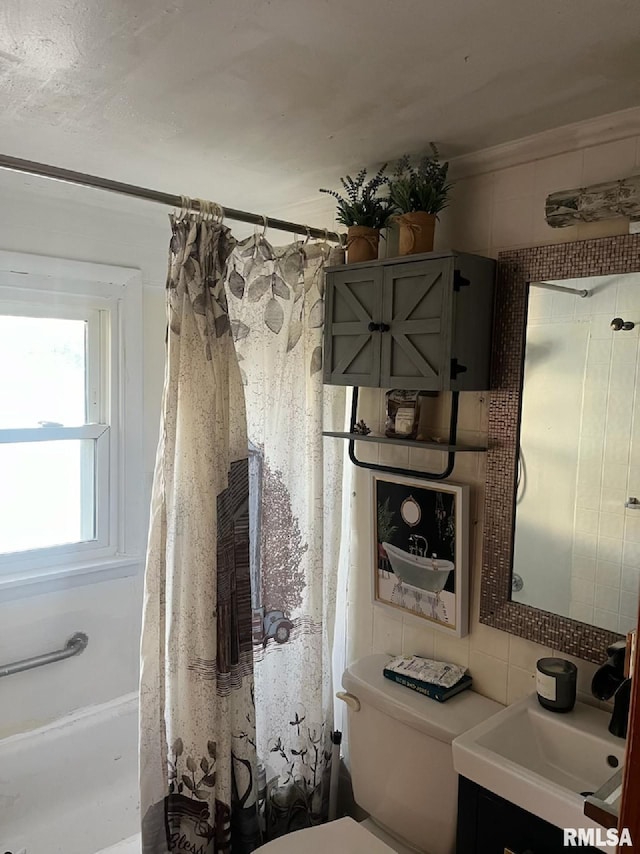 bathroom with vanity, toilet, and tile walls