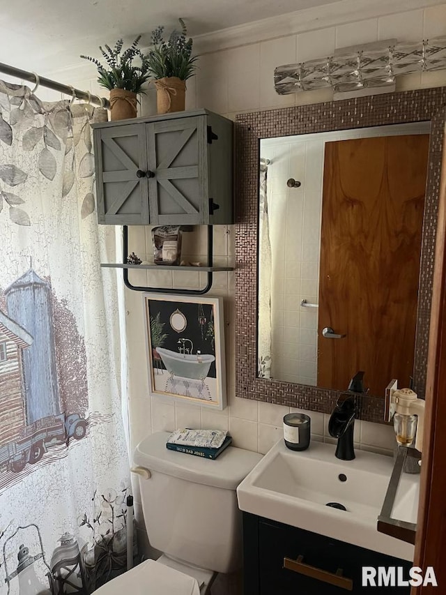 bathroom with vanity, toilet, and tile walls