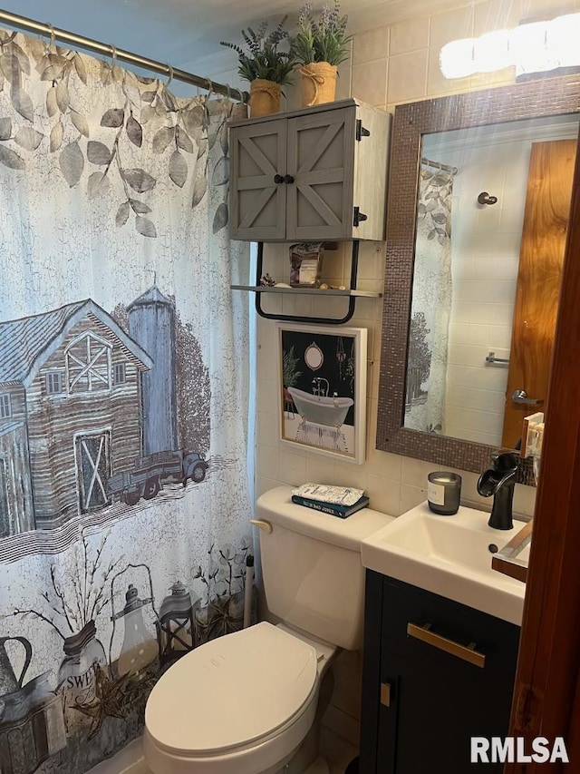 bathroom featuring vanity, tile walls, and toilet