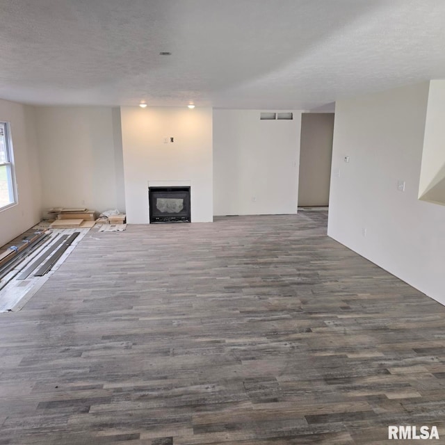 unfurnished living room featuring a textured ceiling and dark hardwood / wood-style floors