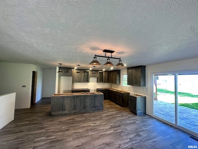 kitchen with dark hardwood / wood-style floors, a center island, a textured ceiling, and hanging light fixtures