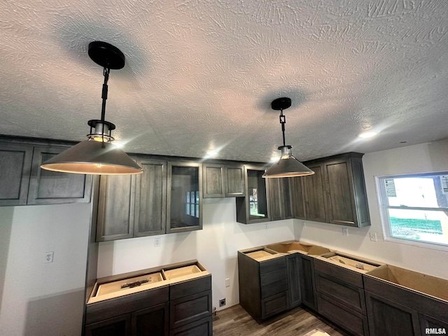 kitchen with dark brown cabinets, hardwood / wood-style floors, pendant lighting, and a textured ceiling