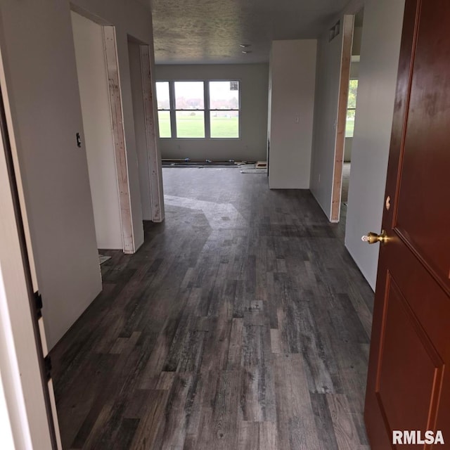 hall featuring dark wood-type flooring and a textured ceiling