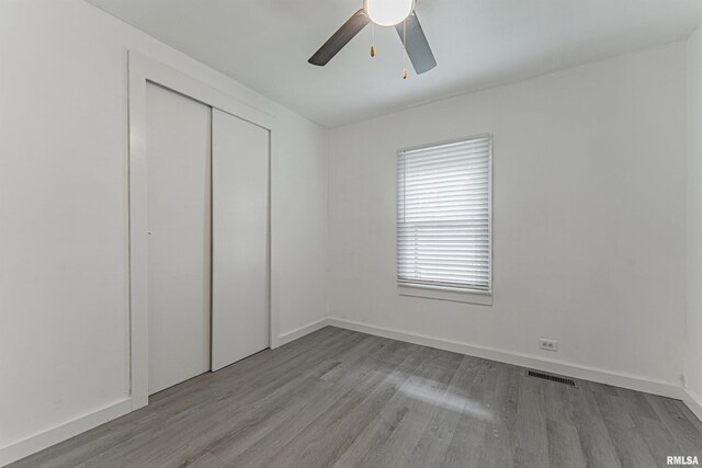 unfurnished bedroom with light wood-type flooring, ceiling fan, and a closet