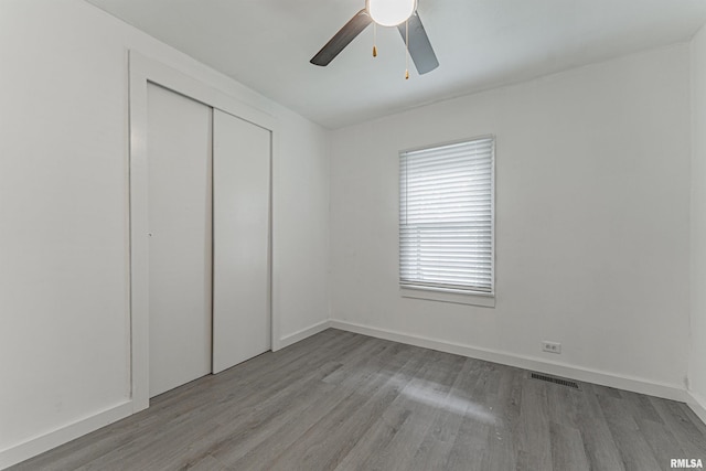 unfurnished bedroom with light hardwood / wood-style floors, a closet, and ceiling fan