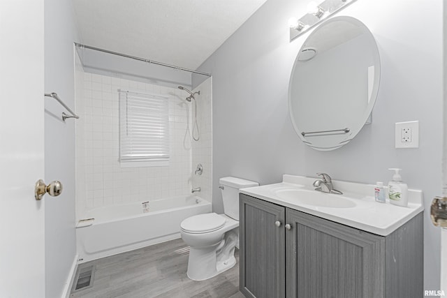 full bathroom with tiled shower / bath combo, vanity, wood-type flooring, and toilet