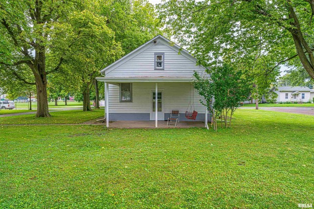 back of house with covered porch and a lawn