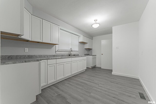 kitchen with sink, light hardwood / wood-style flooring, and white cabinets