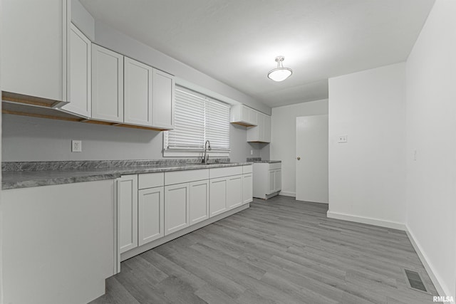 kitchen featuring white cabinetry, sink, and light wood-type flooring