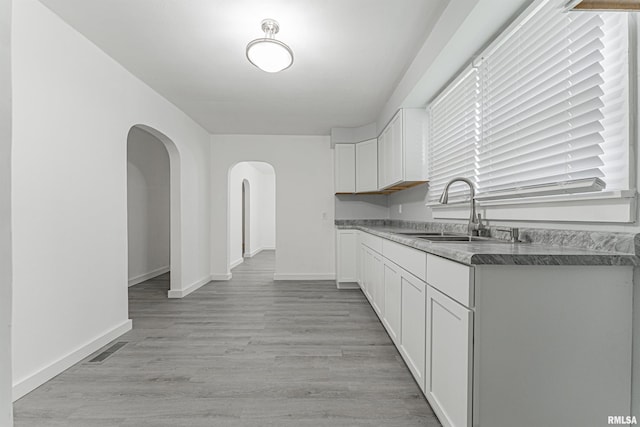 kitchen featuring white cabinets, light hardwood / wood-style flooring, and sink