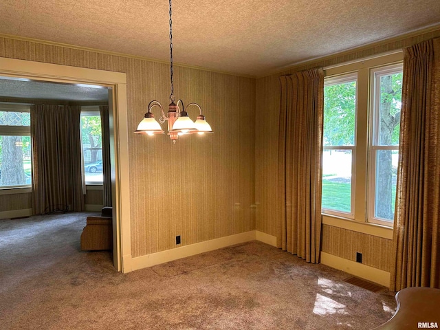 carpeted spare room featuring a notable chandelier and a textured ceiling