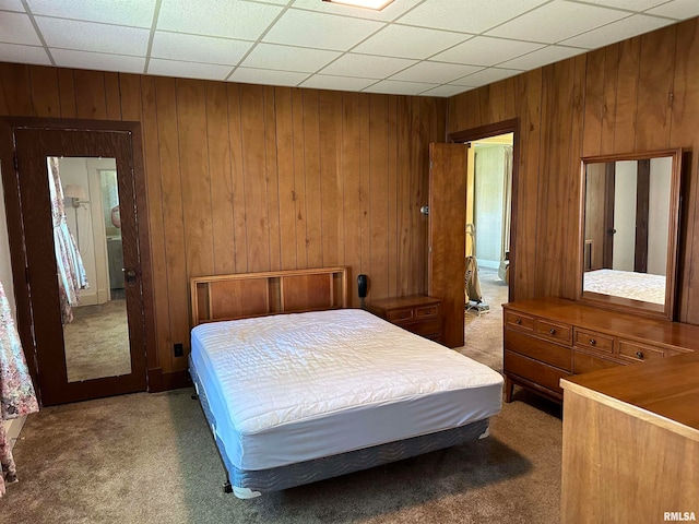 carpeted bedroom with wood walls and a drop ceiling